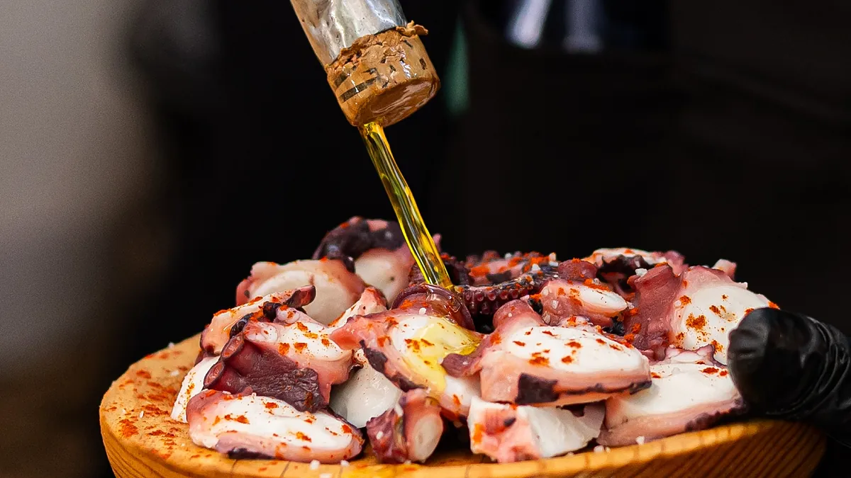 Un cliente mangia il pulpo a feira in un ristorante tradizionale a Melide, Galizia, con un ambiente caldo e familiare