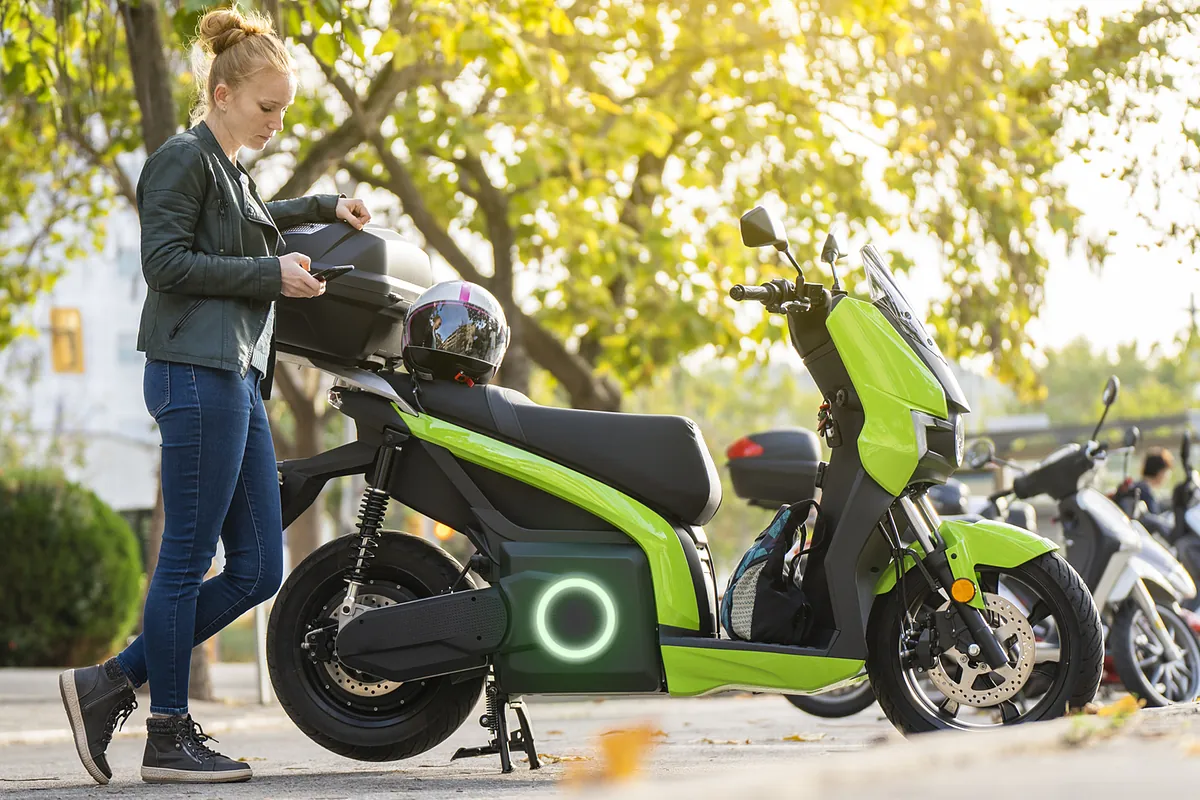 Un motociclista inizia a guidare una moto elettrica, con un cartellino indicante sussidi e incentivi